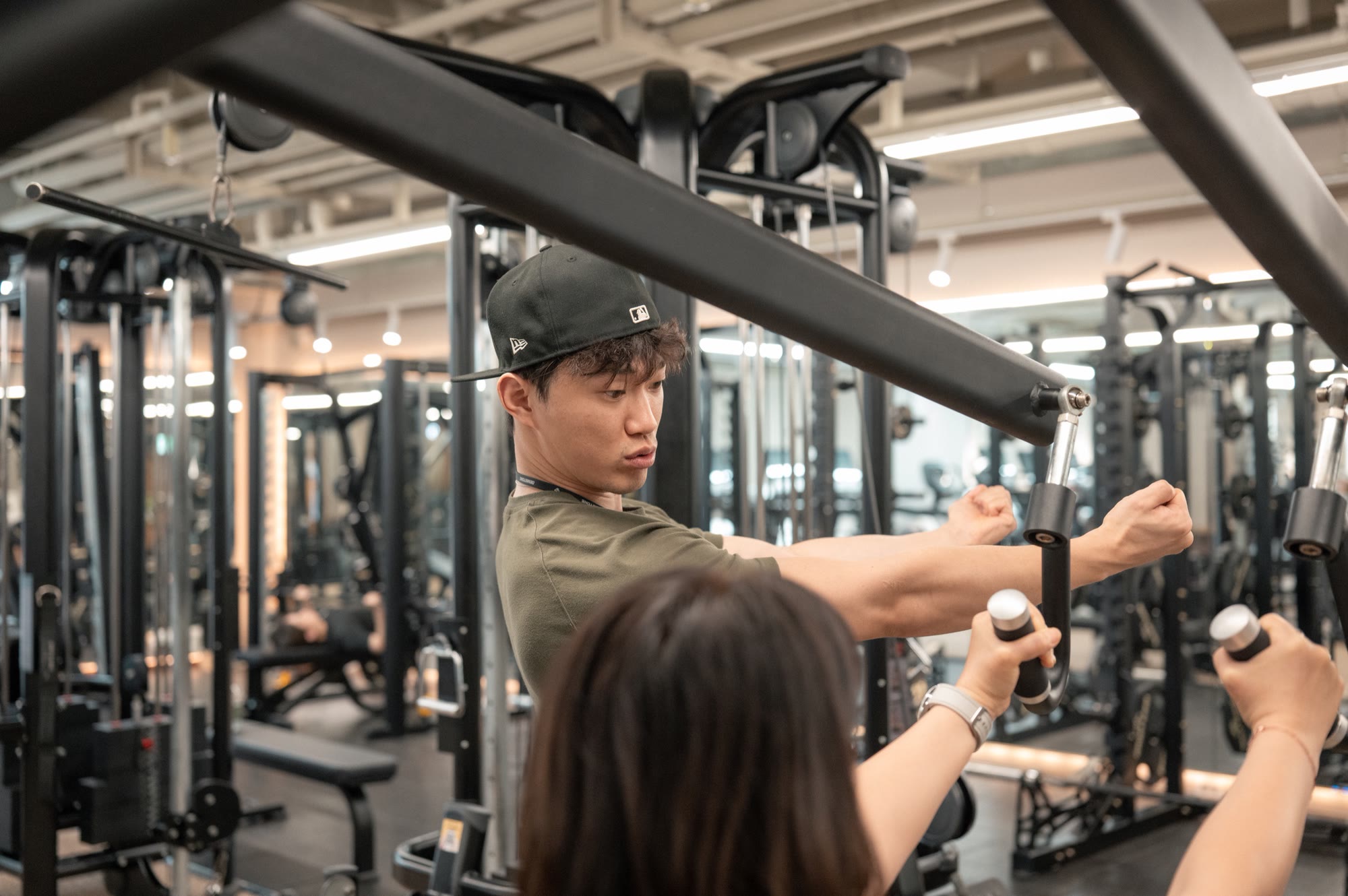 트레이너가 회원에게 기구 사용 방향을 설명하는 장면
